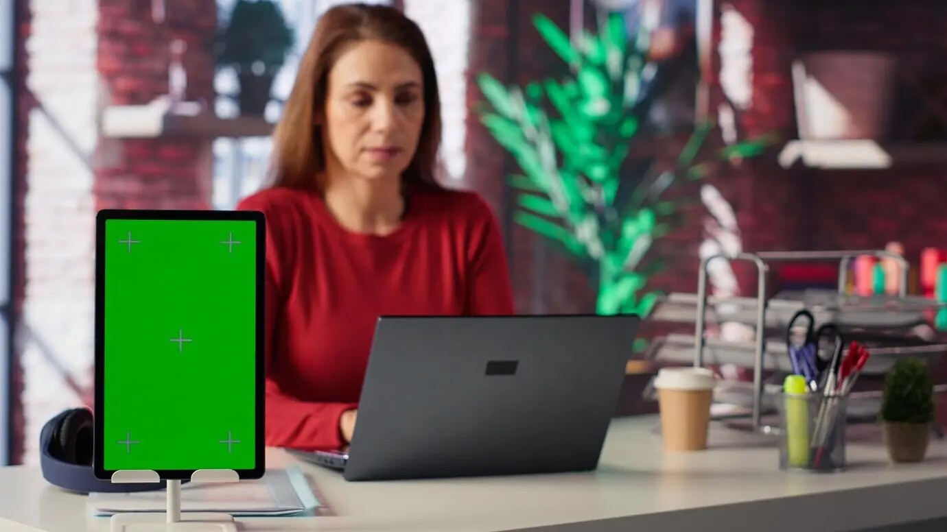 Уверенная в себе женщина решает свои задачи на фриланс-платформе рядом с экраном с макетом.