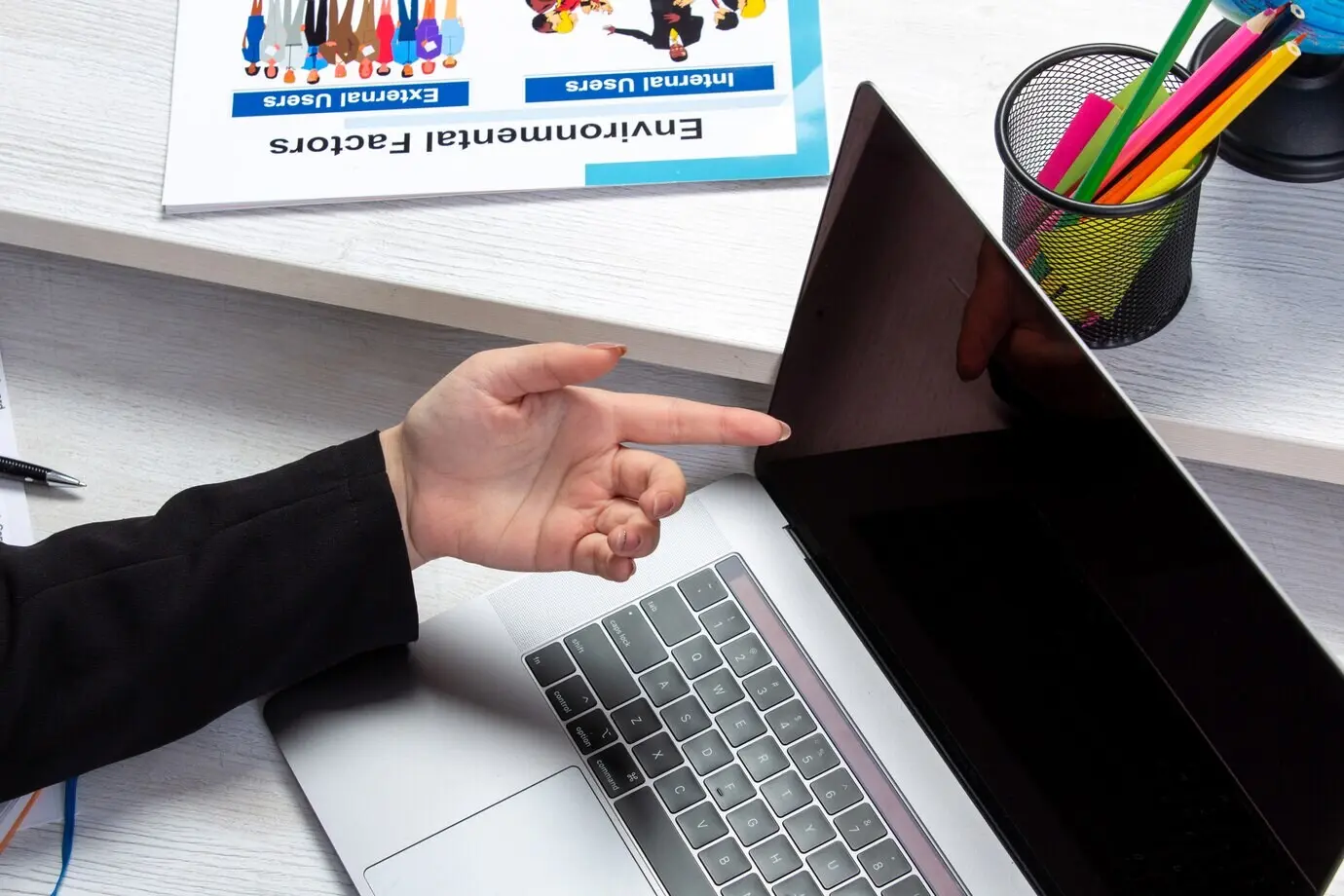 Фронтальный вид: девушка использует ноутбук перед столом с расписаниями и графиками, занимается рабочей деловой деятельностью.